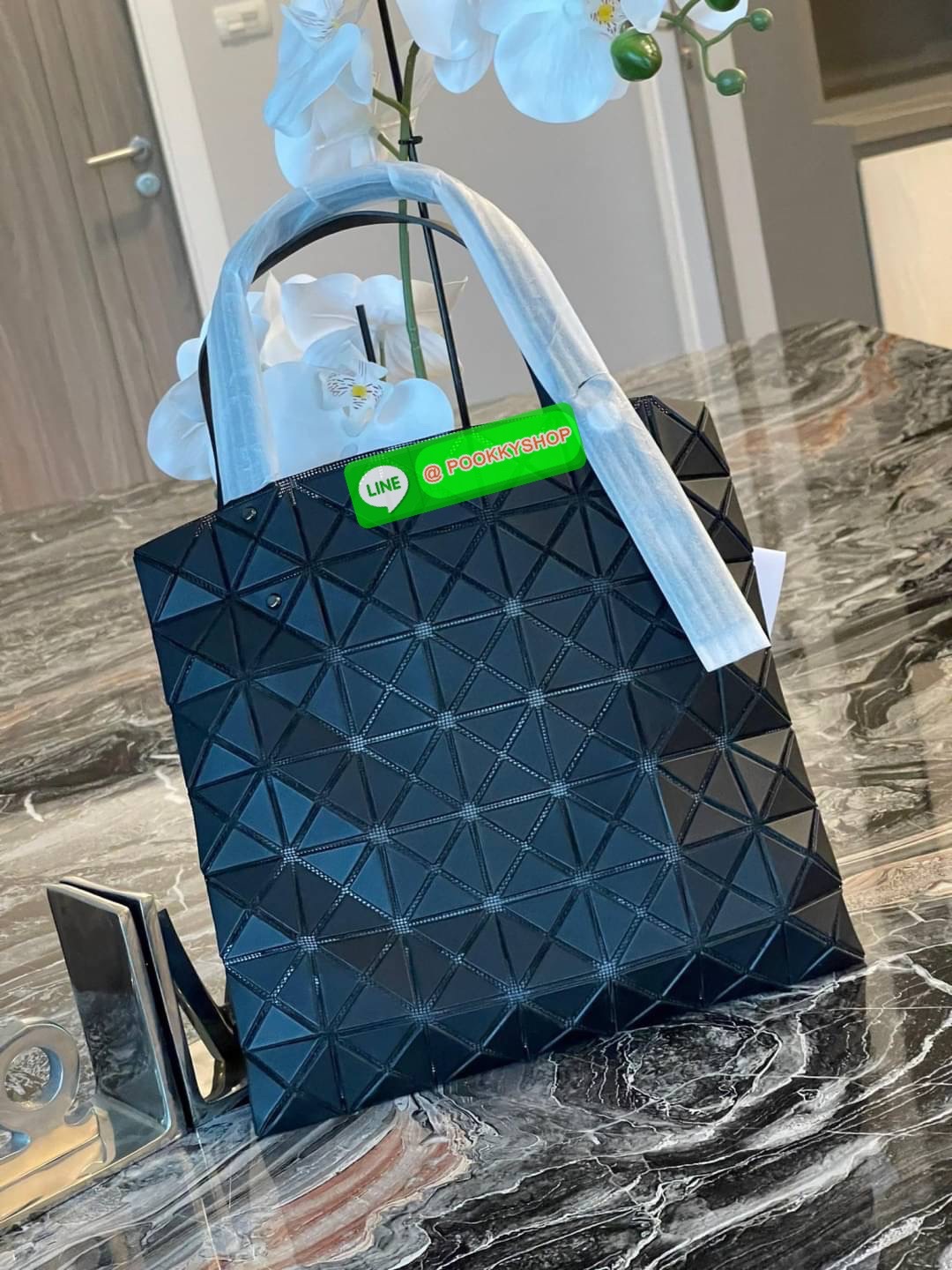 Baobao Issey Miyake Prism Kangaroo tote bag กระเป๋าถือทรงโท้ทที่ประดิษฐ์ขึ้นอย่างเชี่ยวชาญในญี่ปุ่น มาพร้อมแผงเรขาคณิตสำหรับการออกแบบที่ได้รับแรงบันดาลใจจากกระดาษพับ ซิลลูเอทอันเป็นเอกลักษณ์นี้ปิดท้ายด้วยสายรัดแบบอสมมาตร มีการพัฒนาโครงสร้างทรงสามเหลี่ยมเพ