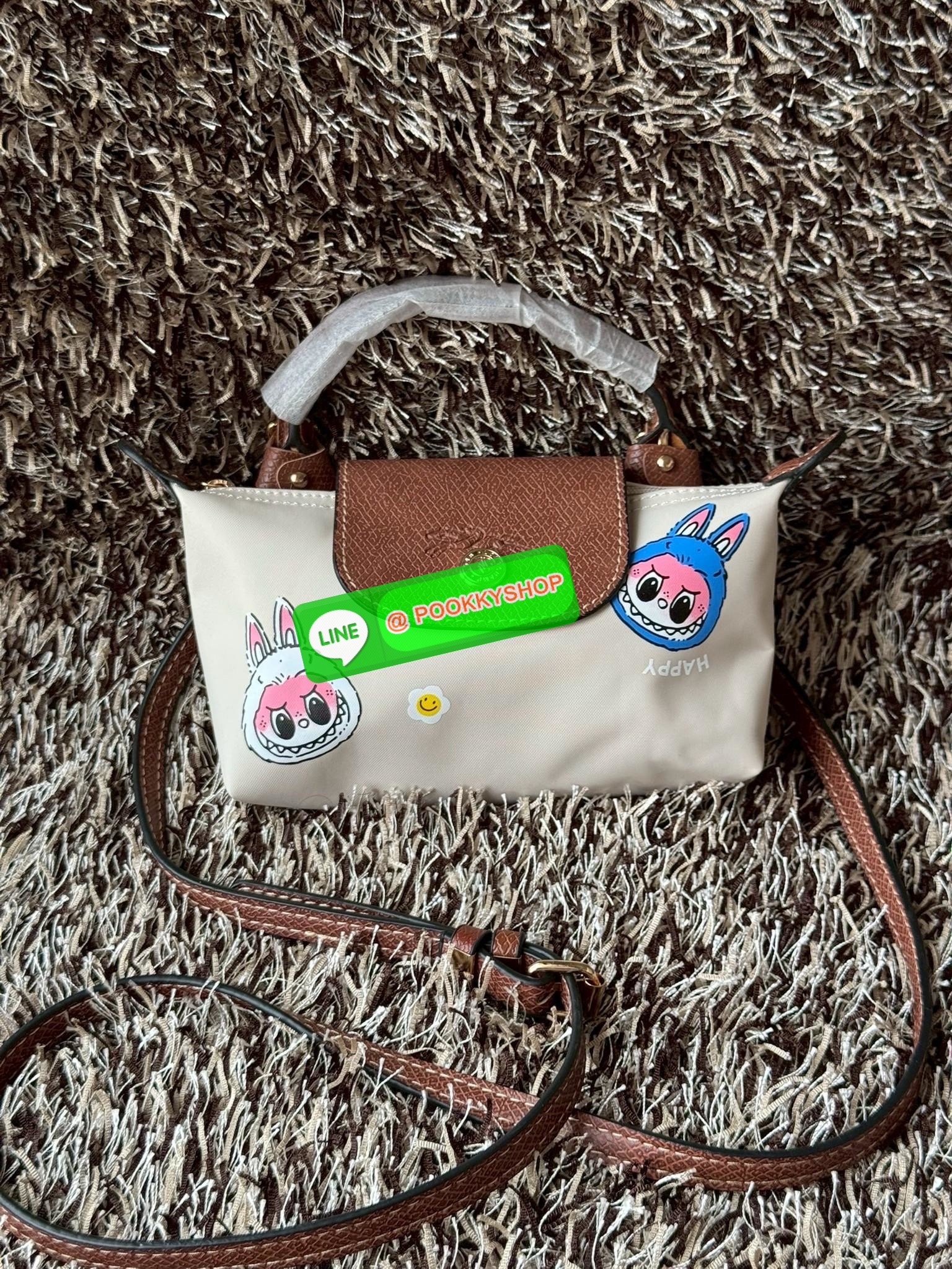 LONGCHAMP LE PLIAGE ORIGINAL X Labubu Pouch with handle เป็นการร่วมงานกัระหว่างแบรนด์ และยังกระเป๋าถือขนาดมินิทรงpouch ที่ด้านหน้ามีลวดลายน้องลาบูบู้ในแบบต่างๆ เปิดปิดระบบสองชั้น ได้ว่าของด้านในมีความปลอดภัย เหมาะอย่างยิ่งสำหรับสาวๆที่ชอบกระเป๋าขนาดมินิไซ