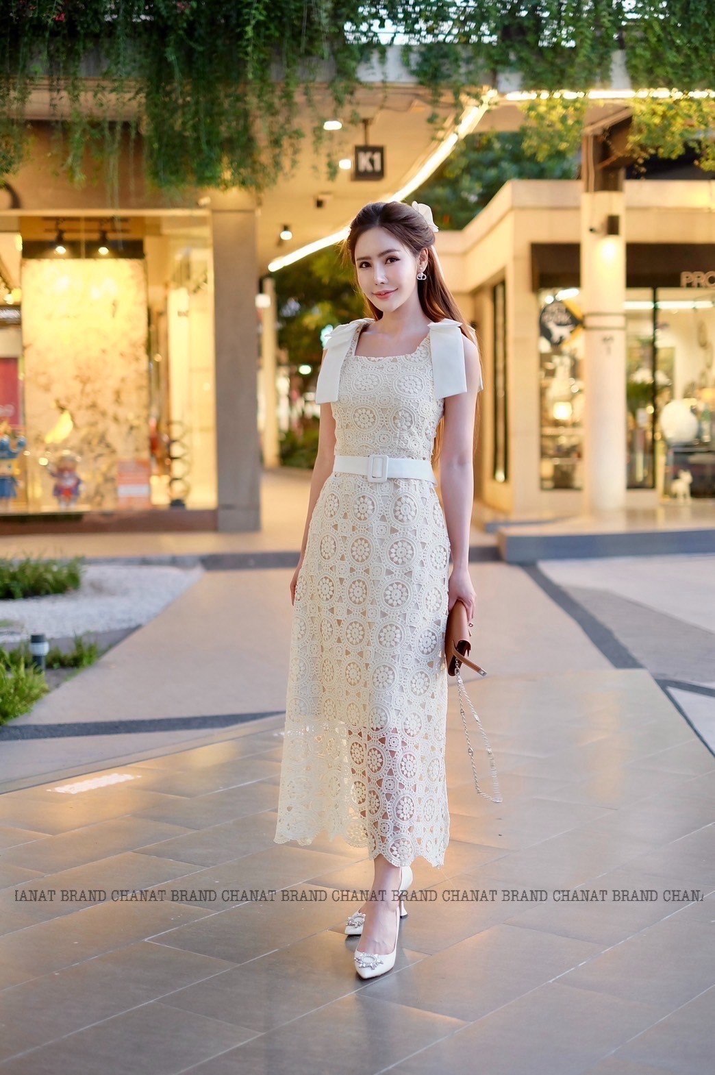 เดรสแฟชั่น เดรสยาวเนื้อผ้าลูกไม้ฉลุวงกลม ดีไซน์แขนกุดตรงบ่าแต่งโบว์ใหญ่สีครีมทั้งสองข้าง