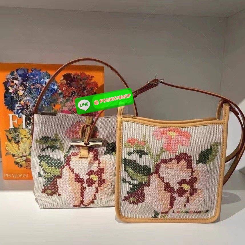 Longchamp Roseau Essential Fleurs กระเป๋าทรงถังขนาดเล็ก วัสดุผ้าฝ้าย ลายปักษ์ดอกกุหลาบ Roseau เป็นคอลเล็คชั่นที่สดใสและเรียบง่าย ซับในสีพื้น อะไหล่สีทอง น้ำหนักเบา จุของได้เยอะ มีสายสะพายไล่ ถอดสายได้ Crossbody ได้