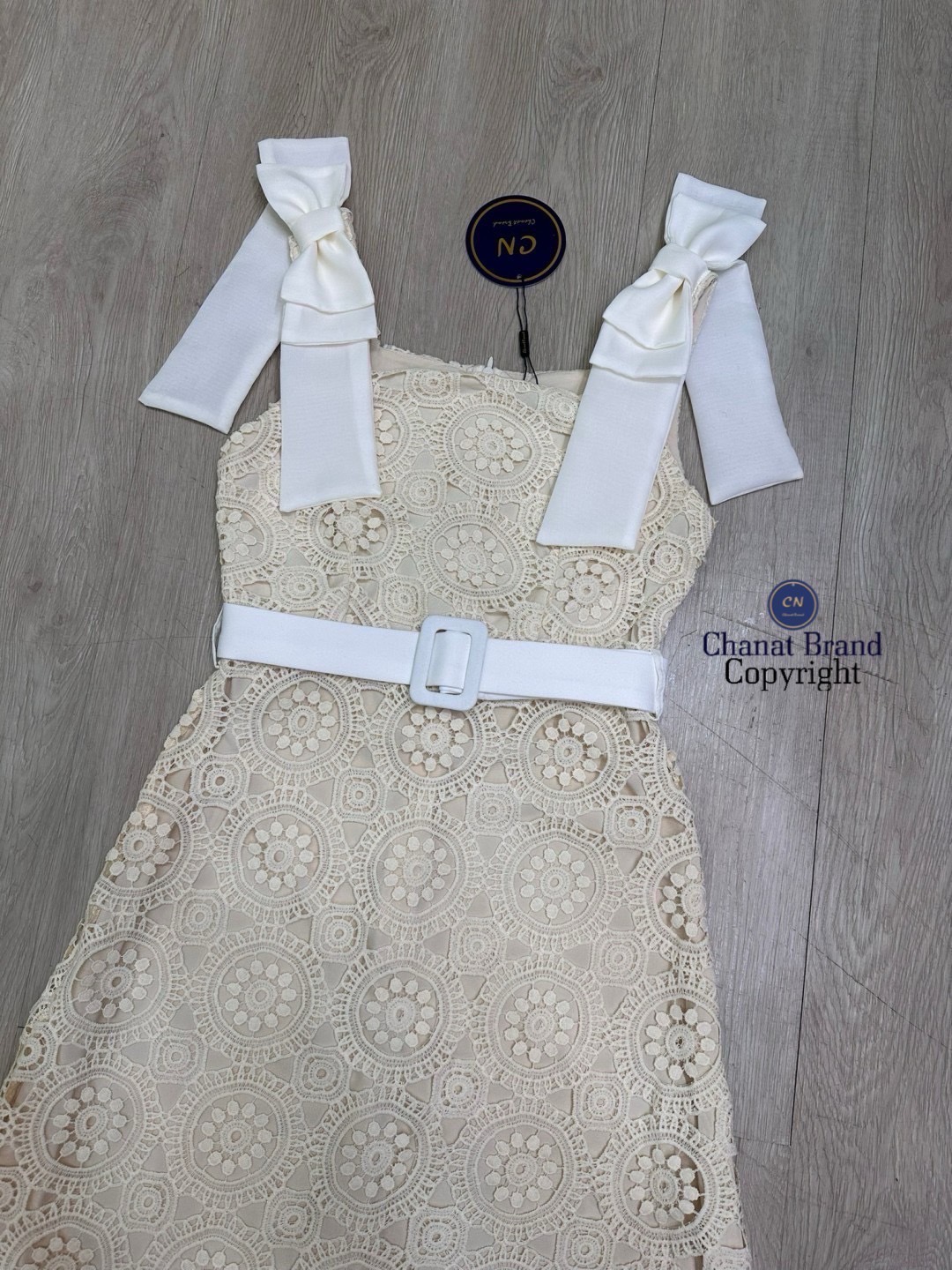 เดรสแฟชั่น เดรสยาวเนื้อผ้าลูกไม้ฉลุวงกลม ดีไซน์แขนกุดตรงบ่าแต่งโบว์ใหญ่สีครีมทั้งสองข้าง