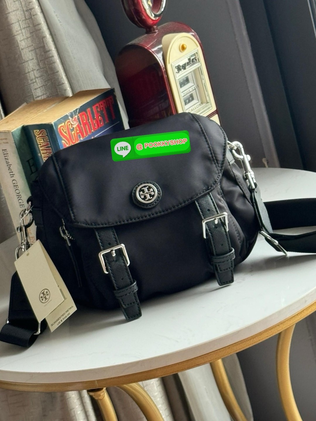TORY BURCH VIRGINIA SMALL MESSENGER เป็นกระเป๋าที่มีรูปแบบการเปิด-ปิดด้วยกระดุมแม่เหล็ก ทำให้ปากกระเป๋าเปิดง่ายและหยิบสิ่งของสะดวก ซึ่งภายในฐานกระเป๋ามีความกว้างขวางพอสมควร เก็บสิ่งของต่าง ๆ ได้ดั่งใจ มาพร้อมดีไซน์เรียบง่ายสีดำประดับด้วยโลโก้แบรนด์อันเป็น