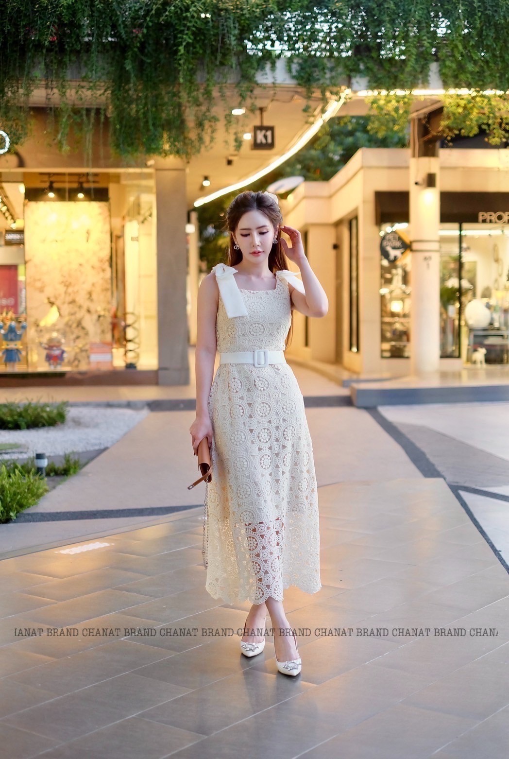 เดรสแฟชั่น เดรสยาวเนื้อผ้าลูกไม้ฉลุวงกลม ดีไซน์แขนกุดตรงบ่าแต่งโบว์ใหญ่สีครีมทั้งสองข้าง