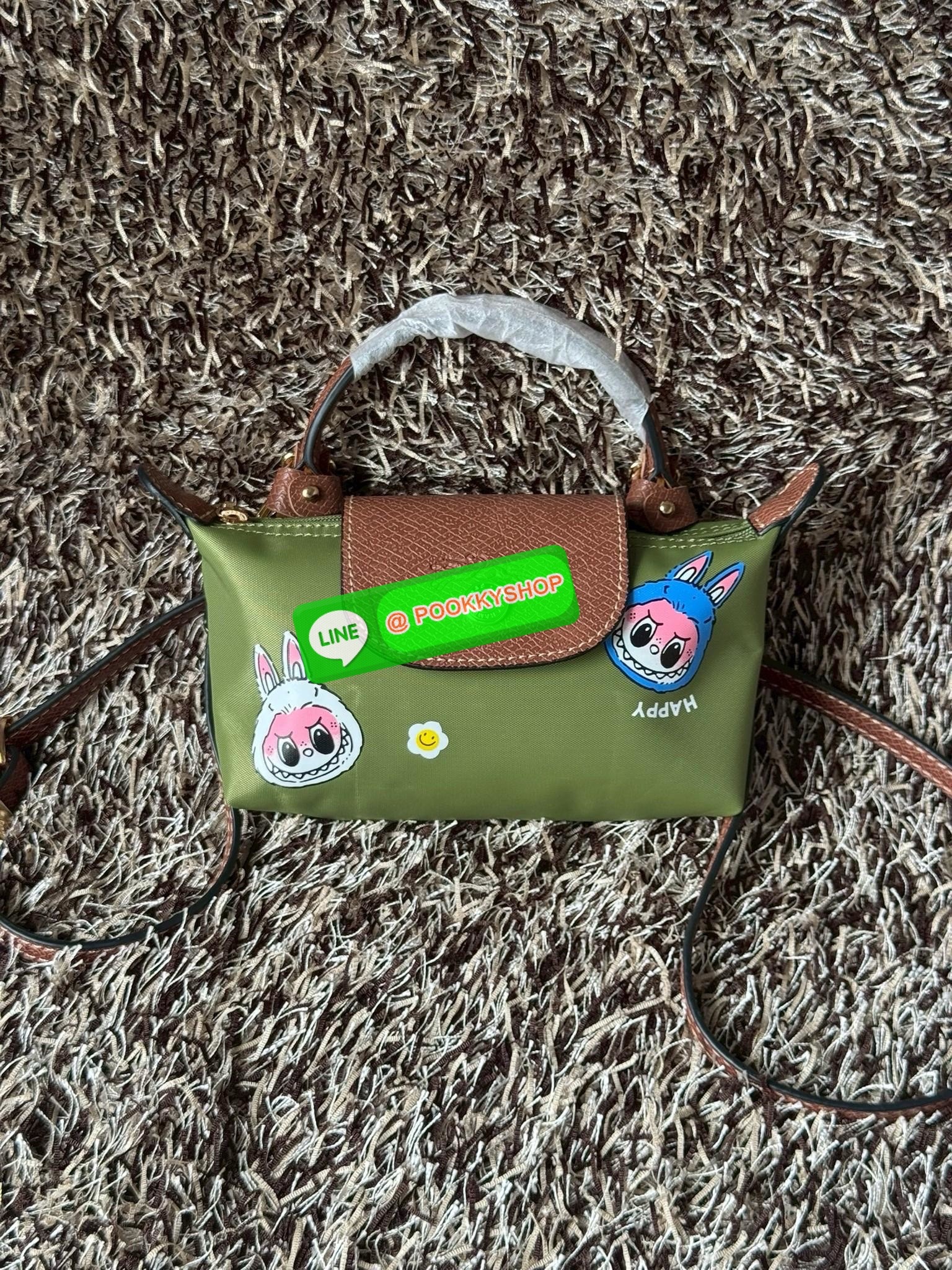 LONGCHAMP LE PLIAGE ORIGINAL X Labubu Pouch with handle เป็นการร่วมงานกัระหว่างแบรนด์ และยังกระเป๋าถือขนาดมินิทรงpouch ที่ด้านหน้ามีลวดลายน้องลาบูบู้ในแบบต่างๆ เปิดปิดระบบสองชั้น ได้ว่าของด้านในมีความปลอดภัย เหมาะอย่างยิ่งสำหรับสาวๆที่ชอบกระเป๋าขนาดมินิไซ