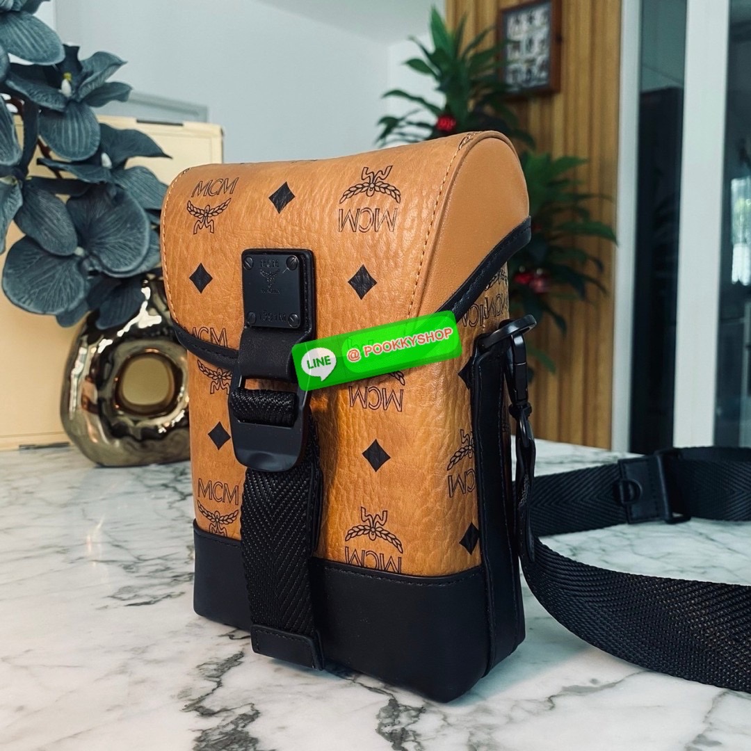 MCM Small Aren N/S Crossbody in Visetos Cognac คอลใหม่เอาใจหนุ่มๆ สั่งก่อนหล่อก่อนน้าา!! กับกระเป๋าสะพายข้างสุดชิค ที่ดูดีมีเสน่ห์มากๆ เห็นแล้วก็ต้องหลงแน่นอน รูปทรงกะทัดรัด สะพายแล้วคล่องตัว เปิด-ปิดด้วยกระดุมแม่เหล็ก ภายในเป็นช่องโล่ง ใส่โทรศัพท์ได้ทุกร