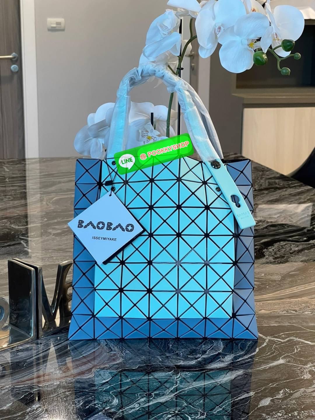 Baobao Issey Miyake Prism Kangaroo tote bag กระเป๋าถือทรงโท้ทที่ประดิษฐ์ขึ้นอย่างเชี่ยวชาญในญี่ปุ่น มาพร้อมแผงเรขาคณิตสำหรับการออกแบบที่ได้รับแรงบันดาลใจจากกระดาษพับ ซิลลูเอทอันเป็นเอกลักษณ์นี้ปิดท้ายด้วยสายรัดแบบอสมมาตร มีการพัฒนาโครงสร้างทรงสามเหลี่ยมเพ