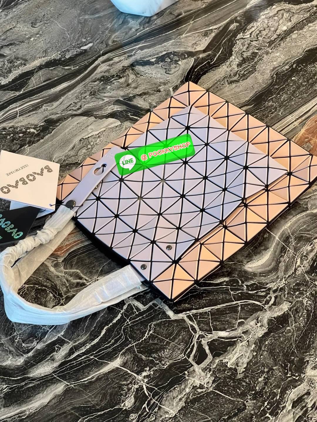 Baobao Issey Miyake Prism Kangaroo tote bag กระเป๋าถือทรงโท้ทที่ประดิษฐ์ขึ้นอย่างเชี่ยวชาญในญี่ปุ่น มาพร้อมแผงเรขาคณิตสำหรับการออกแบบที่ได้รับแรงบันดาลใจจากกระดาษพับ ซิลลูเอทอันเป็นเอกลักษณ์นี้ปิดท้ายด้วยสายรัดแบบอสมมาตร มีการพัฒนาโครงสร้างทรงสามเหลี่ยมเพ