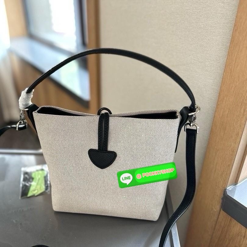 พร้อมส่งที่ไทยอีกครั้ง Longchamp Roseau Bucket Bag S กระเป๋ารุ่นถังไซส์มินิ ที่ขายดีที่สุดในตอนนี้ ตัวกระเป๋าทำจากผ้าแคนวาสเนื้อดี คาดด้วยหนังสีดำ ใบนี้เปิดปิดด้วยตัวคาดยึดด้วยอะไหล่สีเงิน ด้านในใส่ไอแพดมินิ กระเป๋าสตางค์ยาวได้ พร้อมกับหนังรองฐาน สามารถวา