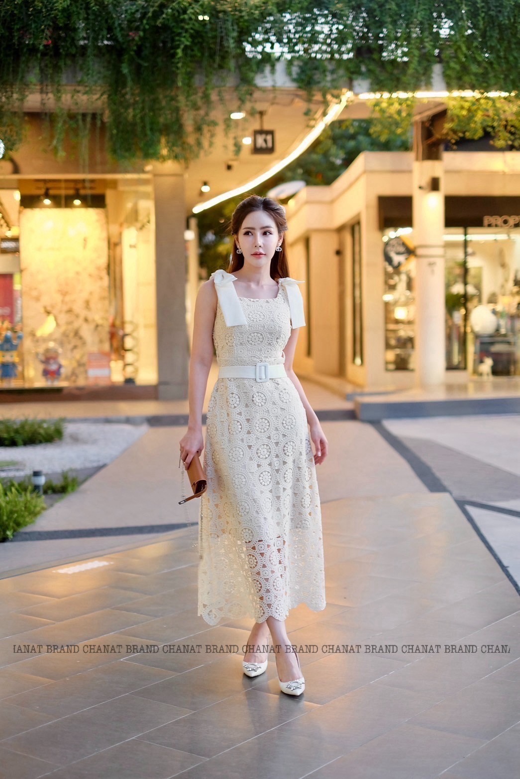 เดรสแฟชั่น เดรสยาวเนื้อผ้าลูกไม้ฉลุวงกลม ดีไซน์แขนกุดตรงบ่าแต่งโบว์ใหญ่สีครีมทั้งสองข้าง