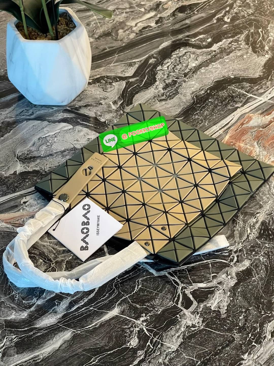 Baobao Issey Miyake Prism Kangaroo tote bag กระเป๋าถือทรงโท้ทที่ประดิษฐ์ขึ้นอย่างเชี่ยวชาญในญี่ปุ่น มาพร้อมแผงเรขาคณิตสำหรับการออกแบบที่ได้รับแรงบันดาลใจจากกระดาษพับ ซิลลูเอทอันเป็นเอกลักษณ์นี้ปิดท้ายด้วยสายรัดแบบอสมมาตร มีการพัฒนาโครงสร้างทรงสามเหลี่ยมเพ