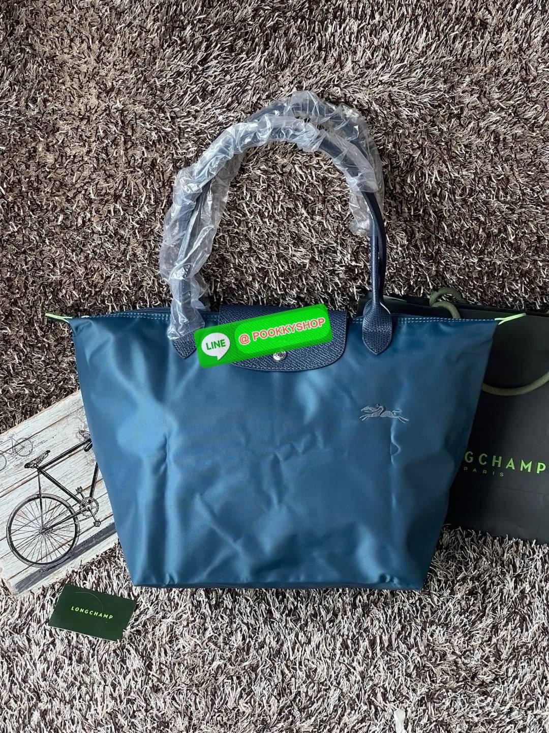 LONGCHAMP LE PLIAGE GREEN Shoulder bag L กระเป๋าโท้ทใบนี้ดึงดูดใจคุณด้วยรูปทรงมินิมอลและปริมาตรที่เพียงพอซึ่งสามารถเก็บเอกสารหรือแล็ปท็อปทั้งหมดของคุณได้อย่างง่ายดาย ด้ามยาวช่วยให้คุณสวมใส่ได้อย่างสบายบนไหล่ ขณะที่การปิดด้วยซิปช่วยให้มั่นใจได้ว่าสิ่งของทั