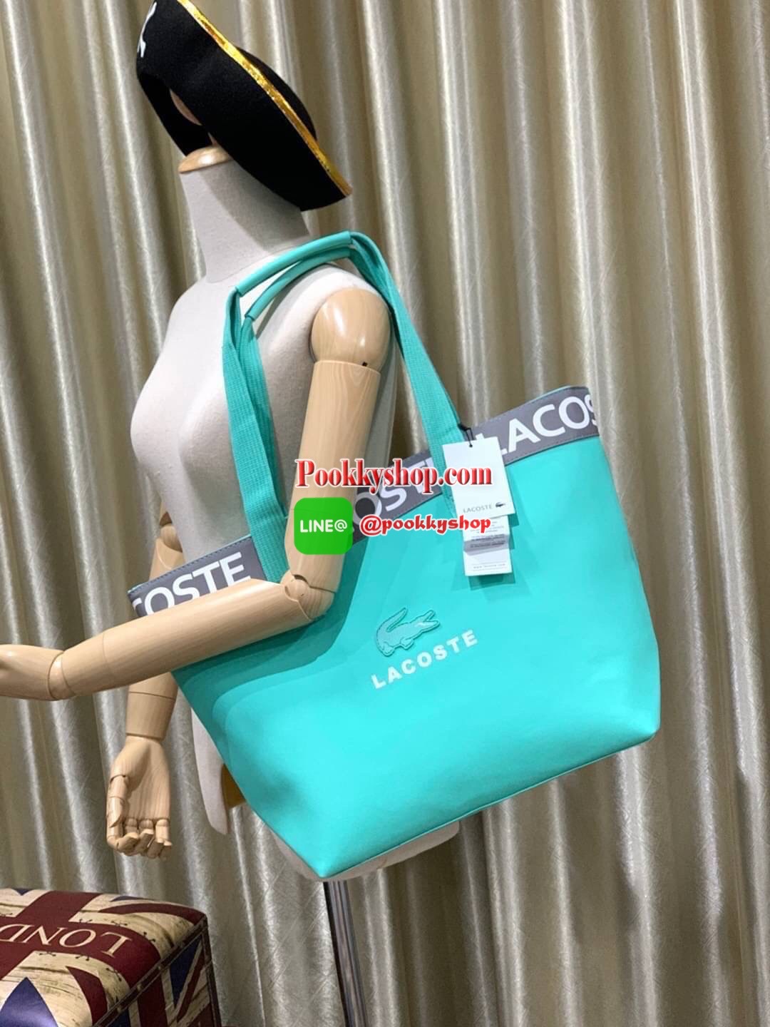 ลาคอส Shopping Bag กระเป๋าถือทรงช้อปปิ้งขนาดใหญ่ ที่ใส่สัมภาระได้รวมถึงใส่เอกสารขนาด A4 ได้ วัสดุ PVC กันน้ำ ดูแลรักษาง่าย ตัดขอบด้วยแถบโลโก้สีเทา ด้านหน้าสกรีนโลโก้และประดับจรเข้อันเป็นสัญลักษณ์ เปิดปิดด้วยซิปเดียว ภายในสกรีนโลโก้แบรนด์ ใบใหญ่สวยโดดเด่