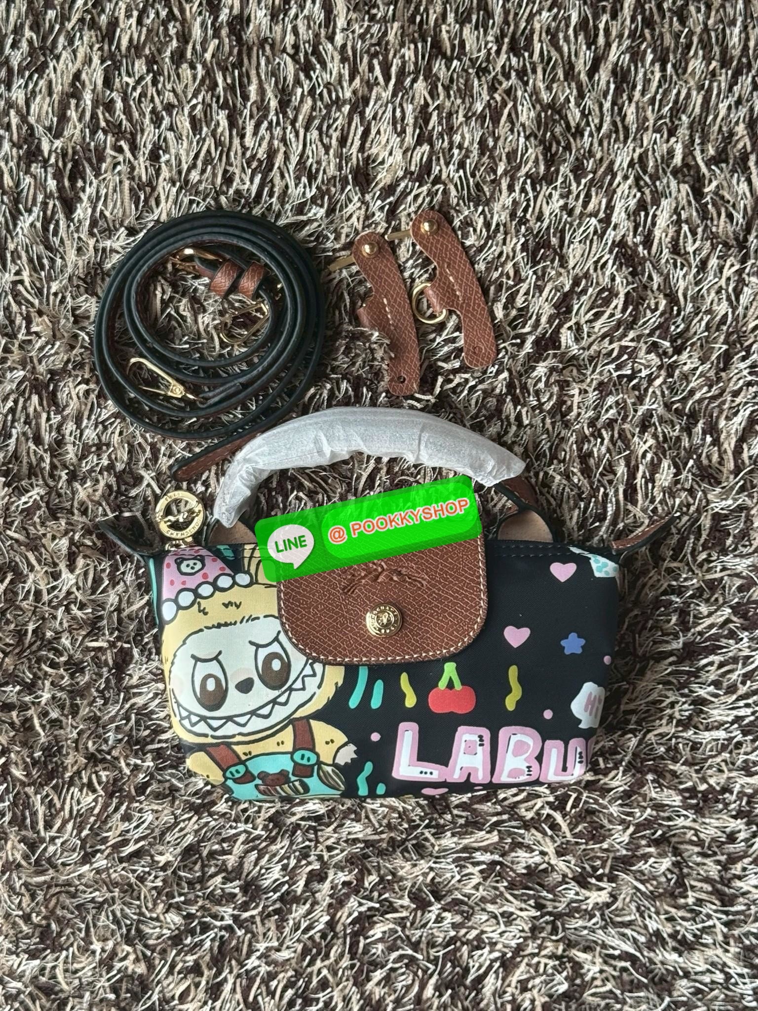 LONGCHAMP LE PLIAGE ORIGINAL X Labubu Pouch with handle เป็นการร่วมงานกัระหว่างแบรนด์ และยังกระเป๋าถือขนาดมินิทรงpouch ที่ด้านหน้ามีลวดลายน้องลาบูบู้ในแบบต่างๆ เปิดปิดระบบสองชั้น ได้ว่าของด้านในมีความปลอดภัย เหมาะอย่างยิ่งสำหรับสาวๆที่ชอบกระเป๋าขนาดมินิไซ
