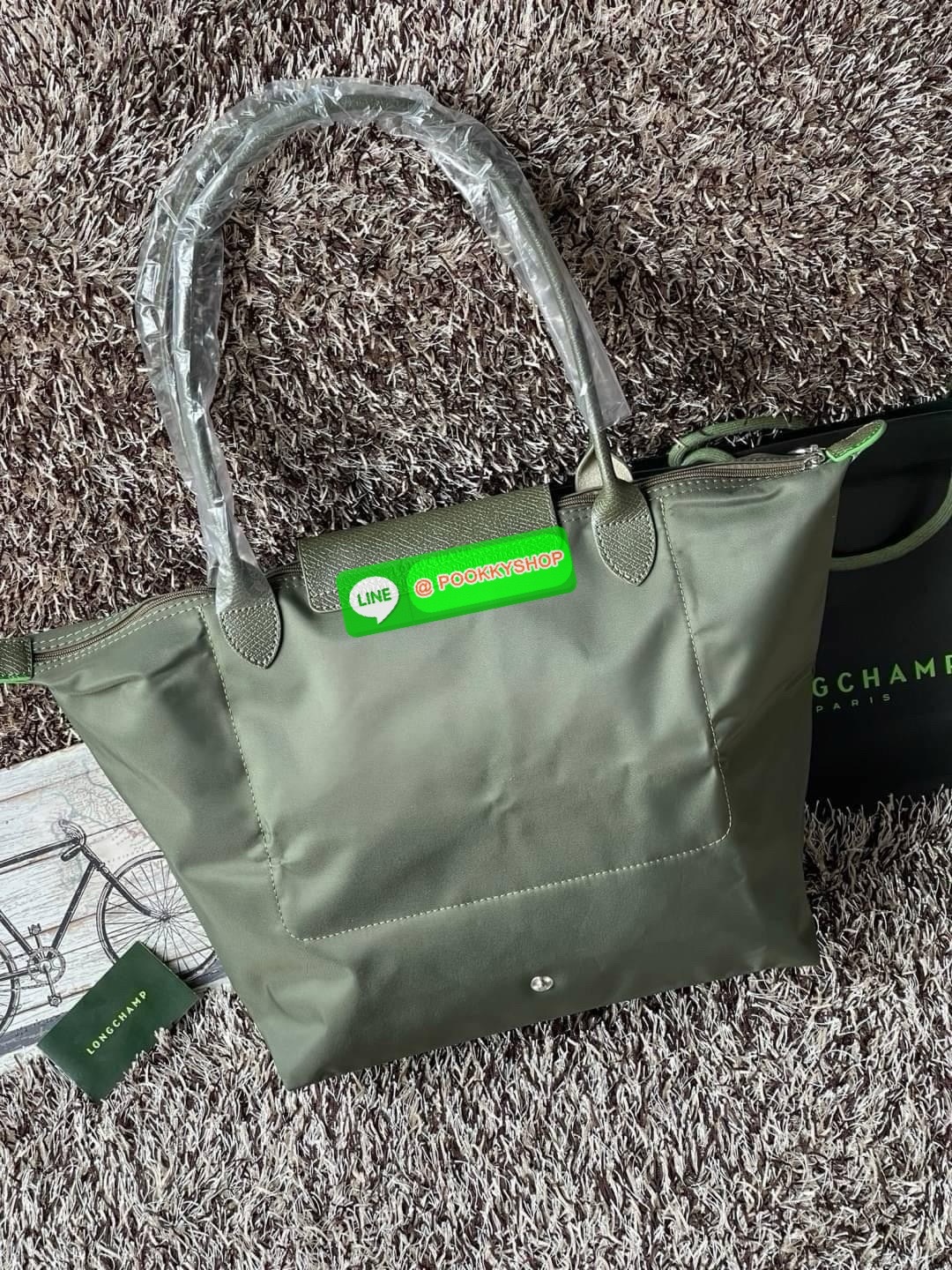 LONGCHAMP LE PLIAGE GREEN Shoulder bag L กระเป๋าโท้ทใบนี้ดึงดูดใจคุณด้วยรูปทรงมินิมอลและปริมาตรที่เพียงพอซึ่งสามารถเก็บเอกสารหรือแล็ปท็อปทั้งหมดของคุณได้อย่างง่ายดาย ด้ามยาวช่วยให้คุณสวมใส่ได้อย่างสบายบนไหล่ ขณะที่การปิดด้วยซิปช่วยให้มั่นใจได้ว่าสิ่งของทั