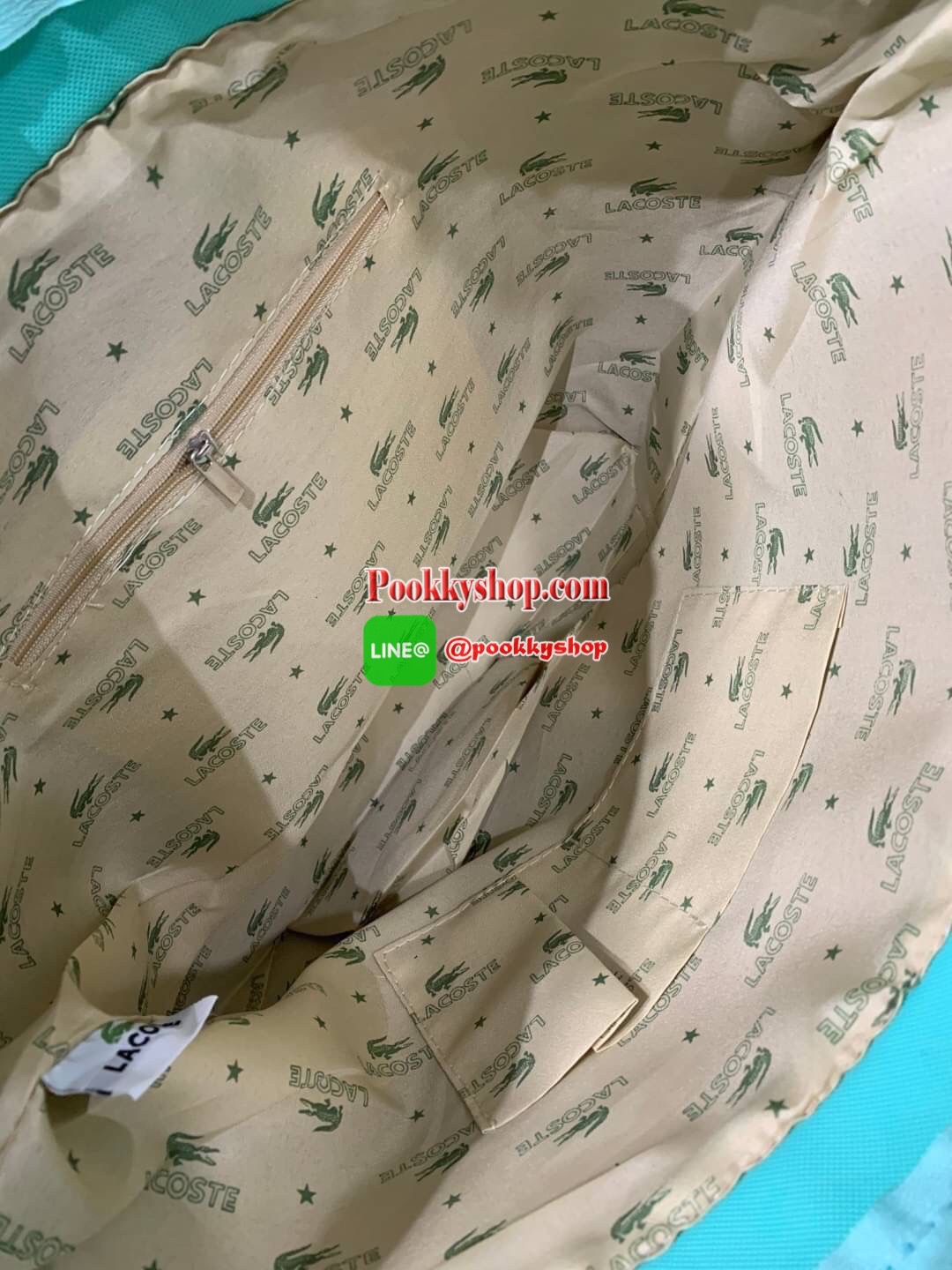 ลาคอส Shopping Bag กระเป๋าถือทรงช้อปปิ้งขนาดใหญ่ ที่ใส่สัมภาระได้รวมถึงใส่เอกสารขนาด A4 ได้ วัสดุ PVC กันน้ำ ดูแลรักษาง่าย ตัดขอบด้วยแถบโลโก้สีเทา ด้านหน้าสกรีนโลโก้และประดับจรเข้อันเป็นสัญลักษณ์ เปิดปิดด้วยซิปเดียว ภายในสกรีนโลโก้แบรนด์ ใบใหญ่สวยโดดเด่