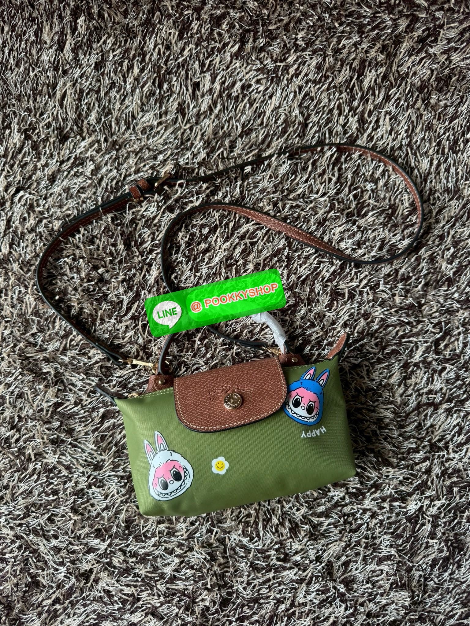 LONGCHAMP LE PLIAGE ORIGINAL X Labubu Pouch with handle เป็นการร่วมงานกัระหว่างแบรนด์ และยังกระเป๋าถือขนาดมินิทรงpouch ที่ด้านหน้ามีลวดลายน้องลาบูบู้ในแบบต่างๆ เปิดปิดระบบสองชั้น ได้ว่าของด้านในมีความปลอดภัย เหมาะอย่างยิ่งสำหรับสาวๆที่ชอบกระเป๋าขนาดมินิไซ