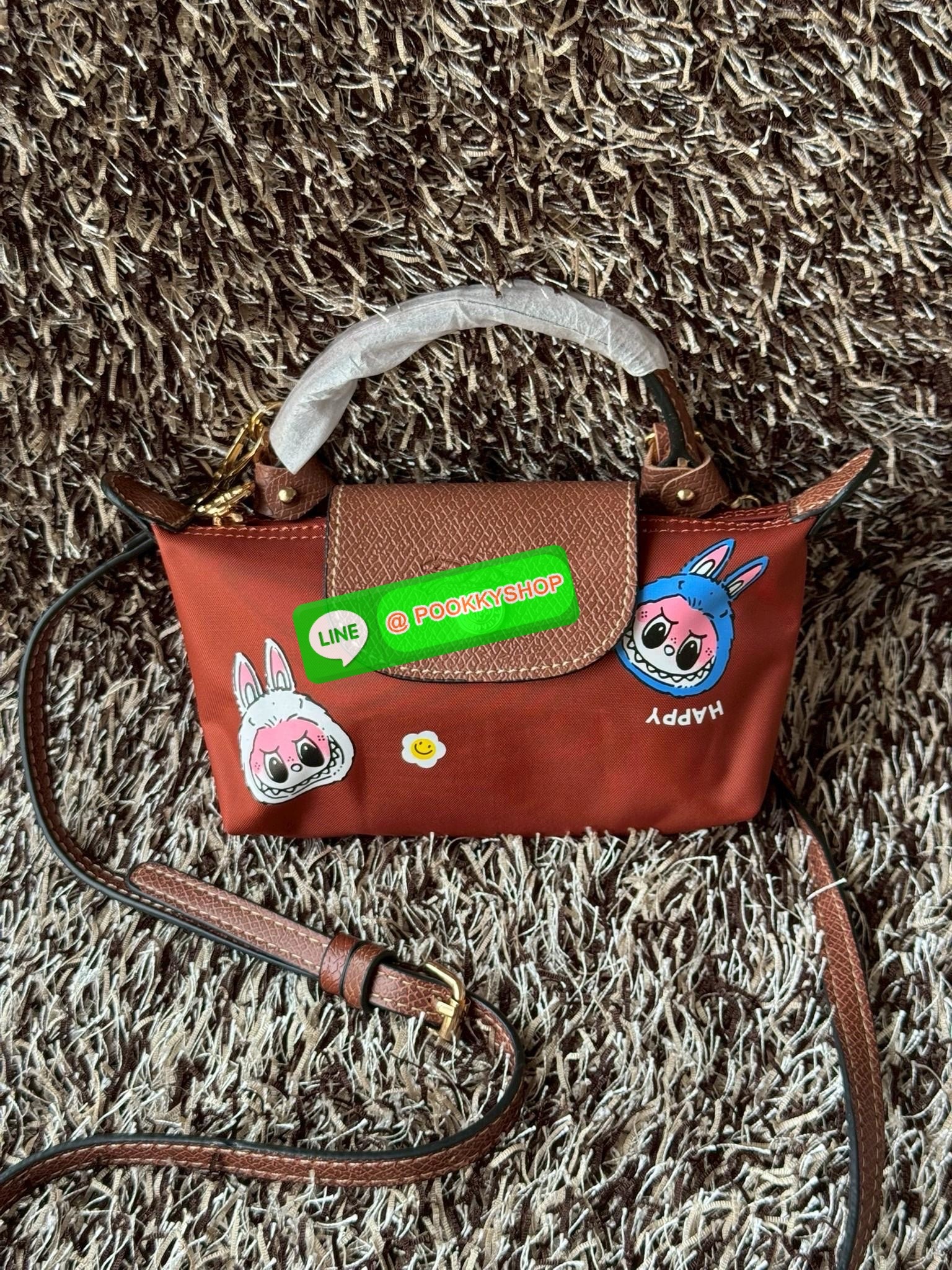 LONGCHAMP LE PLIAGE ORIGINAL X Labubu Pouch with handle เป็นการร่วมงานกัระหว่างแบรนด์ และยังกระเป๋าถือขนาดมินิทรงpouch ที่ด้านหน้ามีลวดลายน้องลาบูบู้ในแบบต่างๆ เปิดปิดระบบสองชั้น ได้ว่าของด้านในมีความปลอดภัย เหมาะอย่างยิ่งสำหรับสาวๆที่ชอบกระเป๋าขนาดมินิไซ