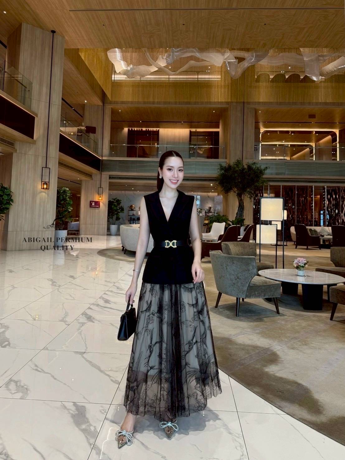 เสื้อแขนกุดเบลเซอร์สีดำ ดีไซน์คอวีลึก เพิ่มความเรียบหรูพร้อมกระดุมด้านหน้าและกระเป๋าดีไซน์เรียบเท่ ดึงความสนใจด้วยเข็มขัดหนังหัวสีทองที่ช่วยเน้นทรวดทรงและเพิ่มความพรีเมียม กระโปรงยาวทรงเอ ผ้าซีทรูสองชั้น ด้านในเป็นผ้าสีเบจเรียบ ส่วนด้านนอกเป็นผ้าทูลล์สีดำ