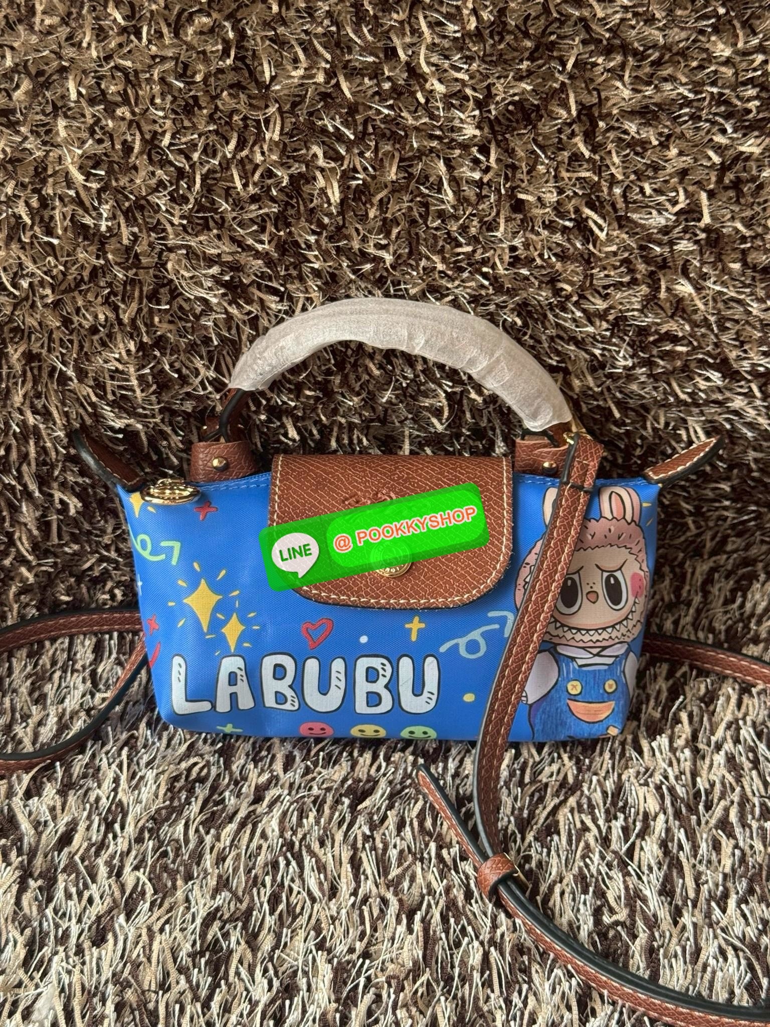 LONGCHAMP LE PLIAGE ORIGINAL X Labubu Pouch with handle เป็นการร่วมงานกัระหว่างแบรนด์ และยังกระเป๋าถือขนาดมินิทรงpouch ที่ด้านหน้ามีลวดลายน้องลาบูบู้ในแบบต่างๆ เปิดปิดระบบสองชั้น ได้ว่าของด้านในมีความปลอดภัย เหมาะอย่างยิ่งสำหรับสาวๆที่ชอบกระเป๋าขนาดมินิไซ