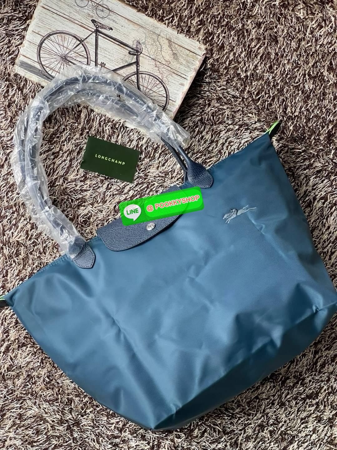 LONGCHAMP LE PLIAGE GREEN Shoulder bag L กระเป๋าโท้ทใบนี้ดึงดูดใจคุณด้วยรูปทรงมินิมอลและปริมาตรที่เพียงพอซึ่งสามารถเก็บเอกสารหรือแล็ปท็อปทั้งหมดของคุณได้อย่างง่ายดาย ด้ามยาวช่วยให้คุณสวมใส่ได้อย่างสบายบนไหล่ ขณะที่การปิดด้วยซิปช่วยให้มั่นใจได้ว่าสิ่งของทั