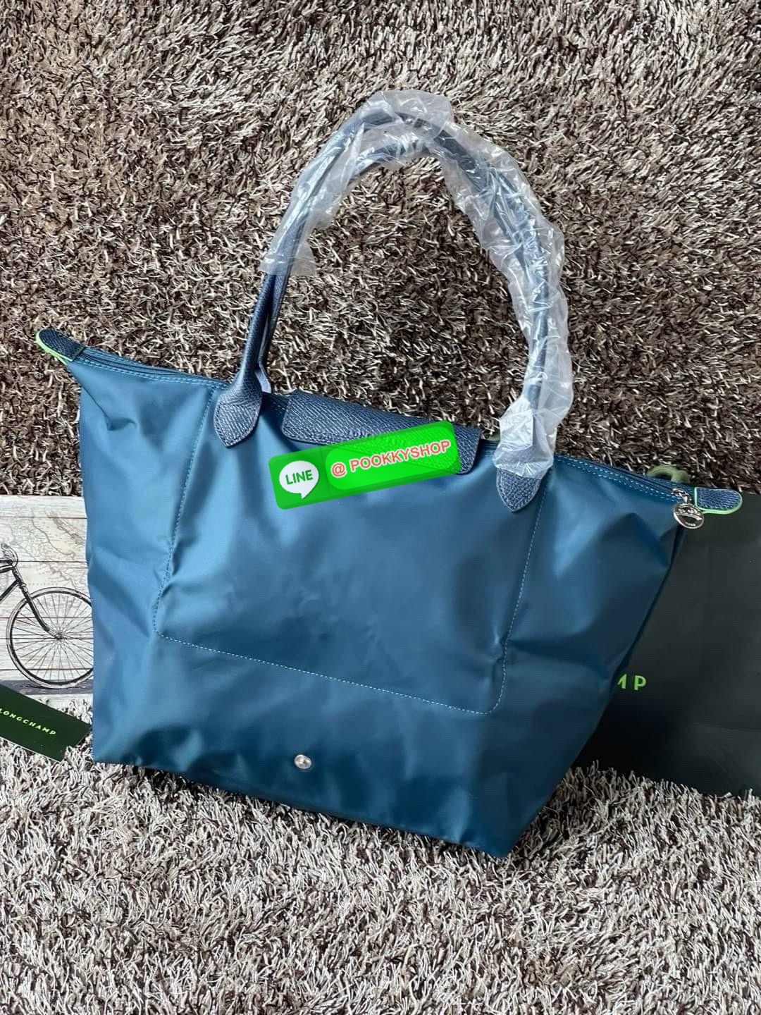LONGCHAMP LE PLIAGE GREEN Shoulder bag L กระเป๋าโท้ทใบนี้ดึงดูดใจคุณด้วยรูปทรงมินิมอลและปริมาตรที่เพียงพอซึ่งสามารถเก็บเอกสารหรือแล็ปท็อปทั้งหมดของคุณได้อย่างง่ายดาย ด้ามยาวช่วยให้คุณสวมใส่ได้อย่างสบายบนไหล่ ขณะที่การปิดด้วยซิปช่วยให้มั่นใจได้ว่าสิ่งของทั