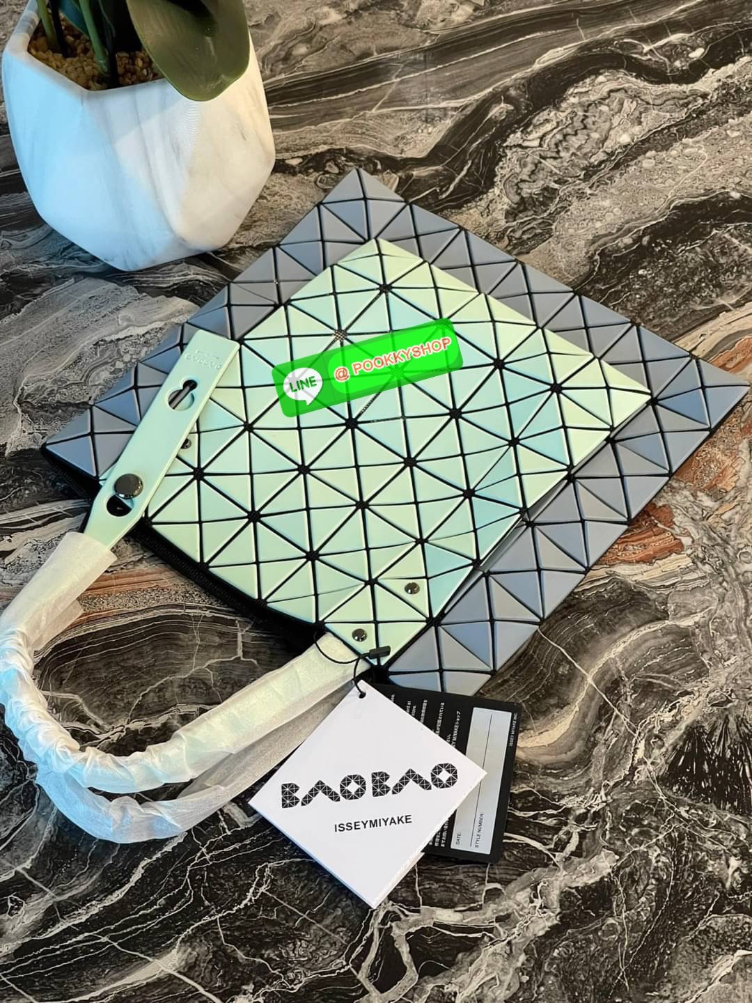 Baobao Issey Miyake Prism Kangaroo tote bag กระเป๋าถือทรงโท้ทที่ประดิษฐ์ขึ้นอย่างเชี่ยวชาญในญี่ปุ่น มาพร้อมแผงเรขาคณิตสำหรับการออกแบบที่ได้รับแรงบันดาลใจจากกระดาษพับ ซิลลูเอทอันเป็นเอกลักษณ์นี้ปิดท้ายด้วยสายรัดแบบอสมมาตร มีการพัฒนาโครงสร้างทรงสามเหลี่ยมเพ