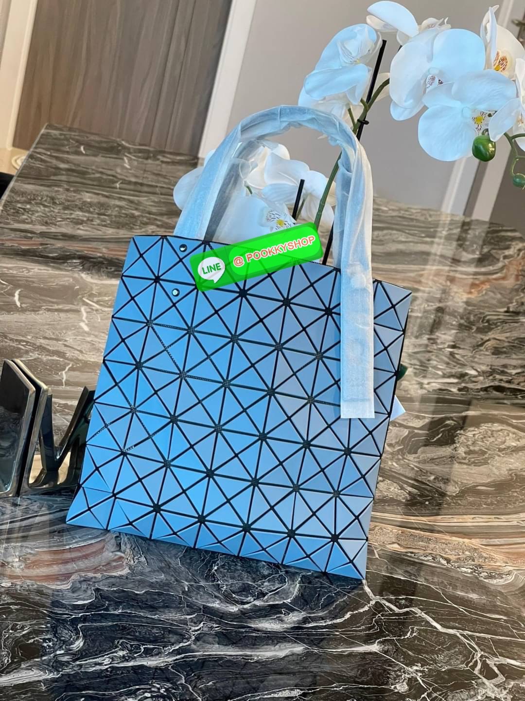 Baobao Issey Miyake Prism Kangaroo tote bag กระเป๋าถือทรงโท้ทที่ประดิษฐ์ขึ้นอย่างเชี่ยวชาญในญี่ปุ่น มาพร้อมแผงเรขาคณิตสำหรับการออกแบบที่ได้รับแรงบันดาลใจจากกระดาษพับ ซิลลูเอทอันเป็นเอกลักษณ์นี้ปิดท้ายด้วยสายรัดแบบอสมมาตร มีการพัฒนาโครงสร้างทรงสามเหลี่ยมเพ