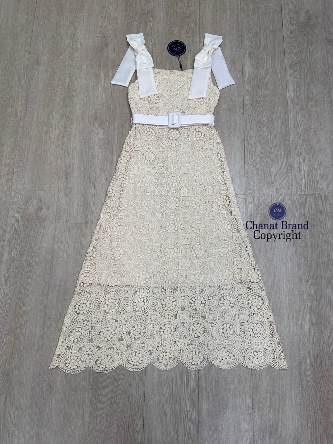 เดรสแฟชั่น เดรสยาวเนื้อผ้าลูกไม้ฉลุวงกลม ดีไซน์แขนกุดตรงบ่าแต่งโบว์ใหญ่สีครีมทั้งสองข้าง