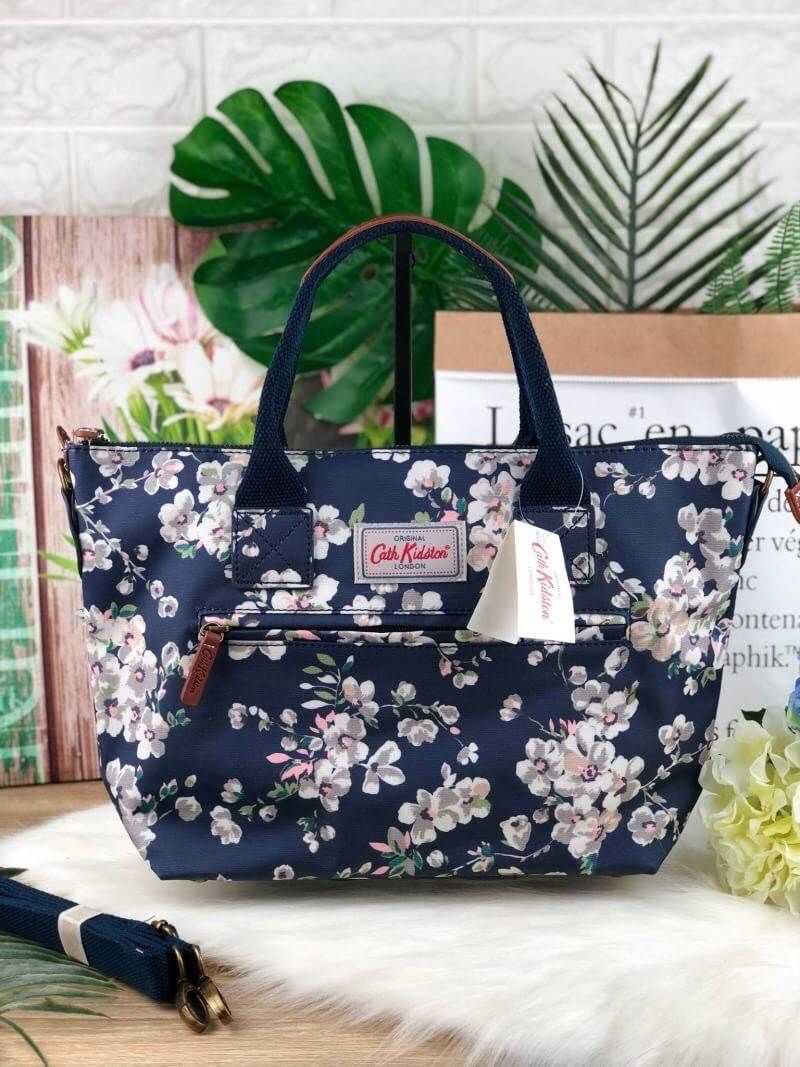 CATH KIDSTON HANDBAG กระเป๋าถือ/สะพายทรงสวย ด้านหน้ามีช่องซิปใส่ของจุกจิกได้ มีหมุดรองฐาน 4 มุม หูหิ้วมีหนังรองมือ เปิดปิดด้วยซิปบน ด้านในกว้างจุของได้เยอะ มีช่องซิปเล็ก 1 ช่อง มาพร้อมสายสะพายยาวถอดและปรับสายได้ รุ่นนี้น้ำหนักเบา ใช้งานง่ายได้หลายโอกาส มี