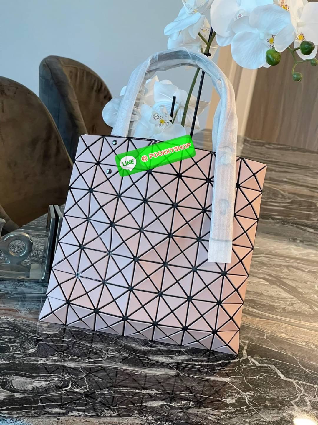 Baobao Issey Miyake Prism Kangaroo tote bag กระเป๋าถือทรงโท้ทที่ประดิษฐ์ขึ้นอย่างเชี่ยวชาญในญี่ปุ่น มาพร้อมแผงเรขาคณิตสำหรับการออกแบบที่ได้รับแรงบันดาลใจจากกระดาษพับ ซิลลูเอทอันเป็นเอกลักษณ์นี้ปิดท้ายด้วยสายรัดแบบอสมมาตร มีการพัฒนาโครงสร้างทรงสามเหลี่ยมเพ