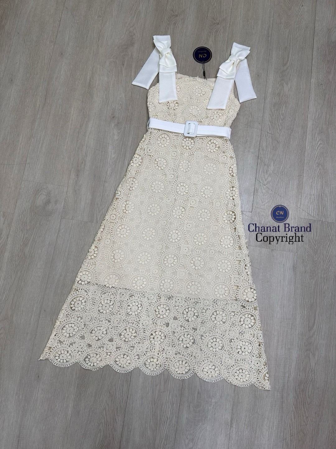 เดรสแฟชั่น เดรสยาวเนื้อผ้าลูกไม้ฉลุวงกลม ดีไซน์แขนกุดตรงบ่าแต่งโบว์ใหญ่สีครีมทั้งสองข้าง