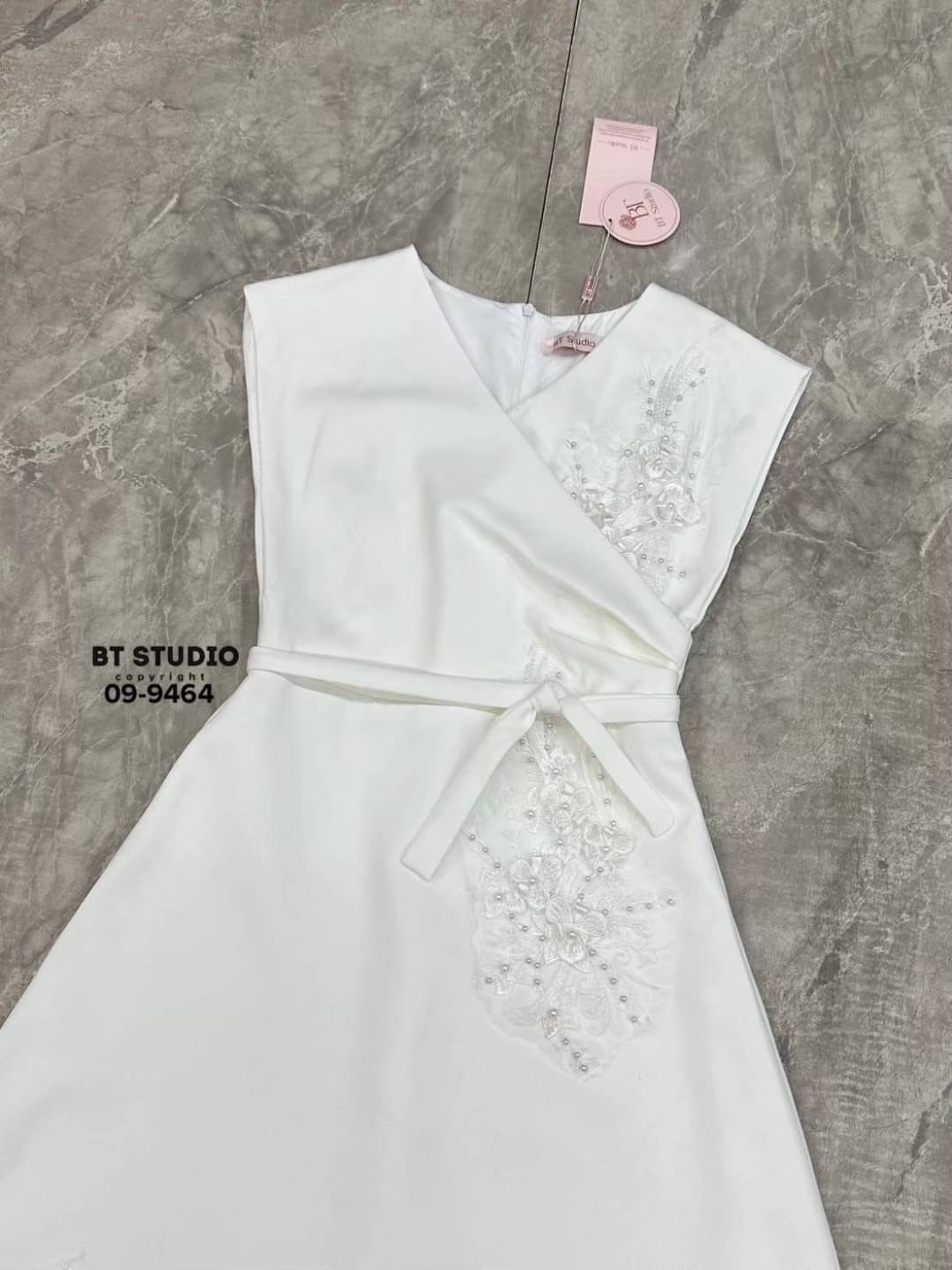 เดรสยาวแขนกุด คอวี ดีไซน์แต่งจับจีบช่วงเอวนึ่งข้าง แต่งปักดอกไม้และมุกด้านหน้าสามจุด ช่วงเอวเข้ารูป ตัวกระโปรงแต่งบานออกเล็กน้อย งานสวยมีซับในซิปหลัง มาพร้อมสายผูกเอว ลุคนี้เรียบหรูดูแพงสุดๆคะ