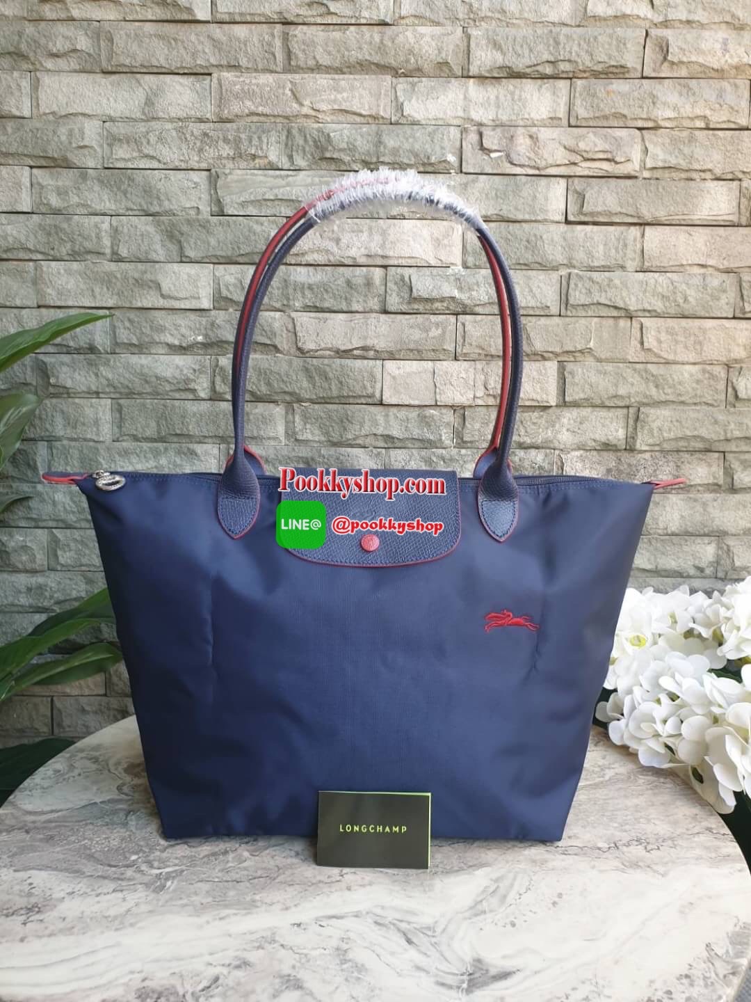 Longchamp Le Pliage Club Tote Bag Size L หูยาว วัสดุเนื้อผ้า Nylon Canvas เคลือบกันนำ้ ตัดด้วยหนังแท้ที่มีน้ำหนักเบา ดีไซน์เรียบง่ายแต่เต็มไปด้วยความคลาสสิก จนเป็นที่ชื่นชอบไปทั่วโลก Longchamp ปรับโฉม LE PLIAGE ด้วยการปักลายรูปม้า-ตราสัญลักษณ์ของแบรนด์บนผ