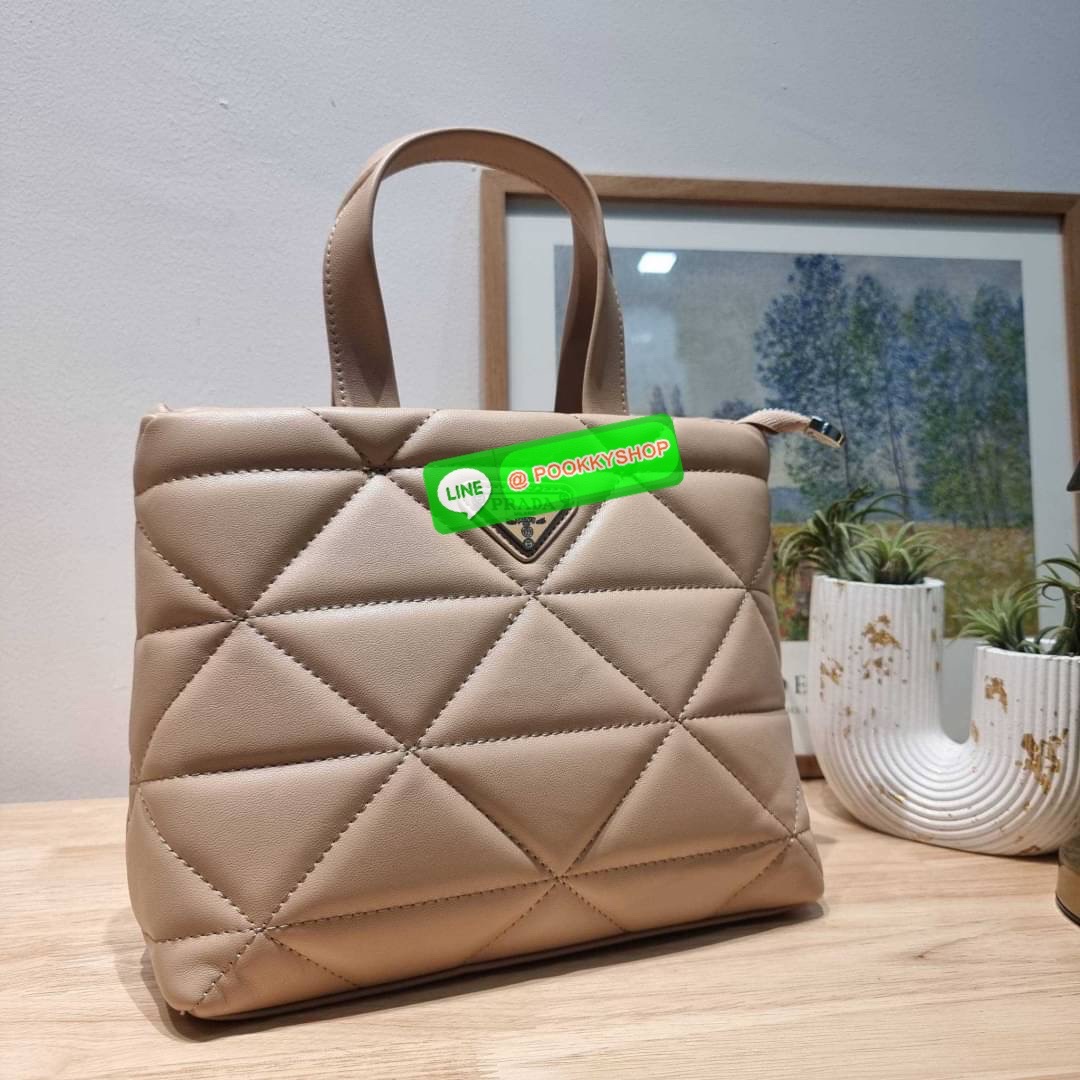 PRADA LEATHER PADDED BAG ใหม่ล่าสุด กับคอลเลคชั่นที่ทำออกมาตอบโจทย์ได้ทุกไลฟ์สไตล์ และเป็นยูนิเซ็กส์ กับกระเป๋าทรงโท้ท ขนาดกำลังดี วัสดุหนังแท้ ตัดเย็บเดินเส้นลายตาราง ปากกระเป๋ามีซิปเปิดปิด ภายในเป็นช่องโล่ง มีช่องแยกให้ มาพร้อมสะพายข้างและใบลูก ให้ได้สน