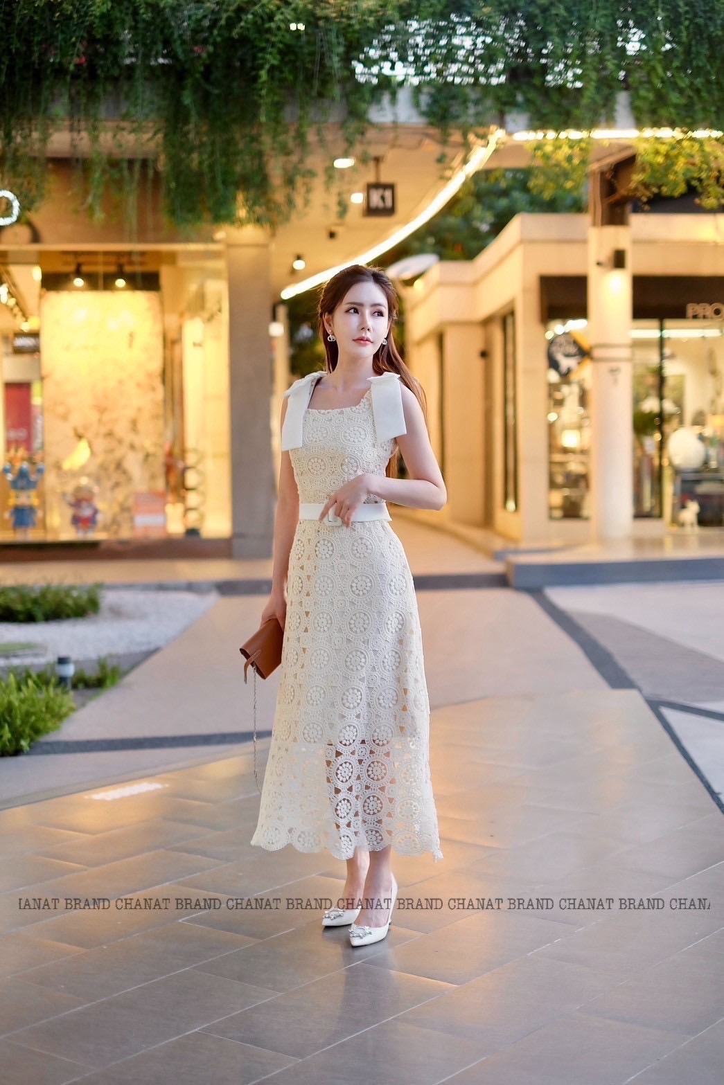 เดรสแฟชั่น เดรสยาวเนื้อผ้าลูกไม้ฉลุวงกลม ดีไซน์แขนกุดตรงบ่าแต่งโบว์ใหญ่สีครีมทั้งสองข้าง