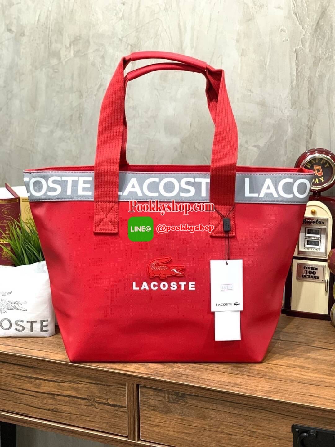 ลาคอส Shopping Bag กระเป๋าถือทรงช้อปปิ้งขนาดใหญ่ ที่ใส่สัมภาระได้รวมถึงใส่เอกสารขนาด A4 ได้ วัสดุ PVC กันน้ำ ดูแลรักษาง่าย ตัดขอบด้วยแถบโลโก้สีเทา ด้านหน้าสกรีนโลโก้และประดับจรเข้อันเป็นสัญลักษณ์ เปิดปิดด้วยซิปเดียว ภายในสกรีนโลโก้แบรนด์ ใบใหญ่สวยโดดเด่