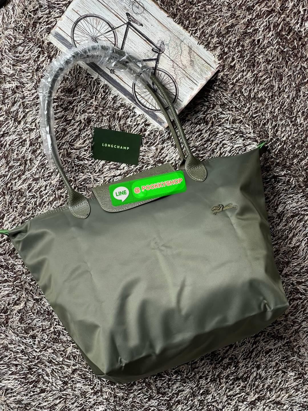 LONGCHAMP LE PLIAGE GREEN Shoulder bag L กระเป๋าโท้ทใบนี้ดึงดูดใจคุณด้วยรูปทรงมินิมอลและปริมาตรที่เพียงพอซึ่งสามารถเก็บเอกสารหรือแล็ปท็อปทั้งหมดของคุณได้อย่างง่ายดาย ด้ามยาวช่วยให้คุณสวมใส่ได้อย่างสบายบนไหล่ ขณะที่การปิดด้วยซิปช่วยให้มั่นใจได้ว่าสิ่งของทั