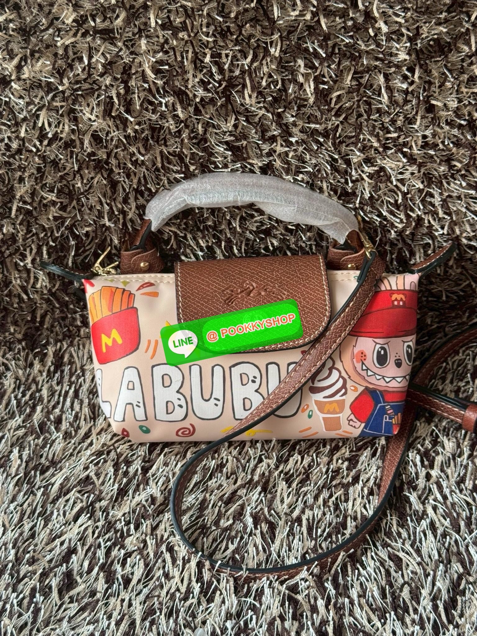 LONGCHAMP LE PLIAGE ORIGINAL X Labubu Pouch with handle เป็นการร่วมงานกัระหว่างแบรนด์ และยังกระเป๋าถือขนาดมินิทรงpouch ที่ด้านหน้ามีลวดลายน้องลาบูบู้ในแบบต่างๆ เปิดปิดระบบสองชั้น ได้ว่าของด้านในมีความปลอดภัย เหมาะอย่างยิ่งสำหรับสาวๆที่ชอบกระเป๋าขนาดมินิไซ