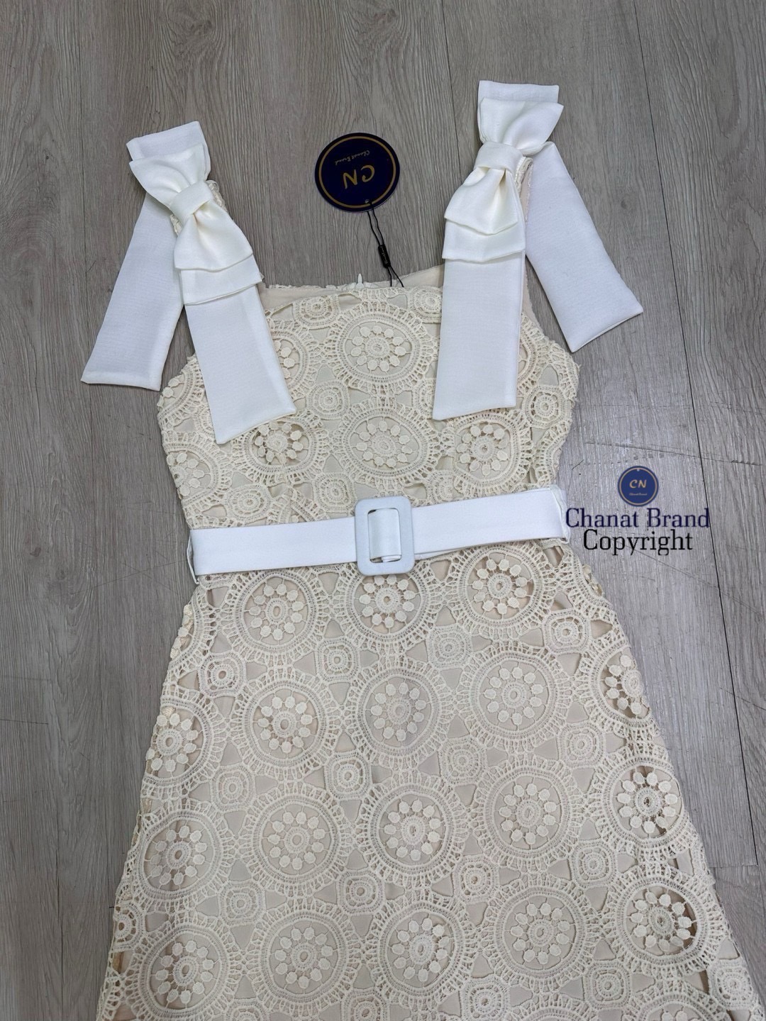 เดรสแฟชั่น เดรสยาวเนื้อผ้าลูกไม้ฉลุวงกลม ดีไซน์แขนกุดตรงบ่าแต่งโบว์ใหญ่สีครีมทั้งสองข้าง