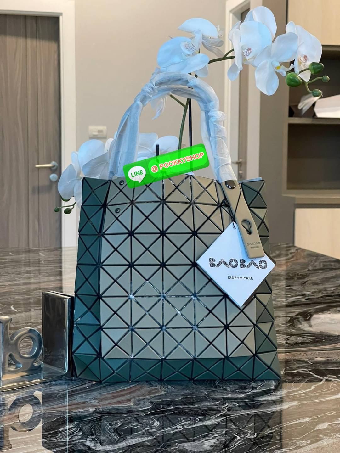 Baobao Issey Miyake Prism Kangaroo tote bag กระเป๋าถือทรงโท้ทที่ประดิษฐ์ขึ้นอย่างเชี่ยวชาญในญี่ปุ่น มาพร้อมแผงเรขาคณิตสำหรับการออกแบบที่ได้รับแรงบันดาลใจจากกระดาษพับ ซิลลูเอทอันเป็นเอกลักษณ์นี้ปิดท้ายด้วยสายรัดแบบอสมมาตร มีการพัฒนาโครงสร้างทรงสามเหลี่ยมเพ