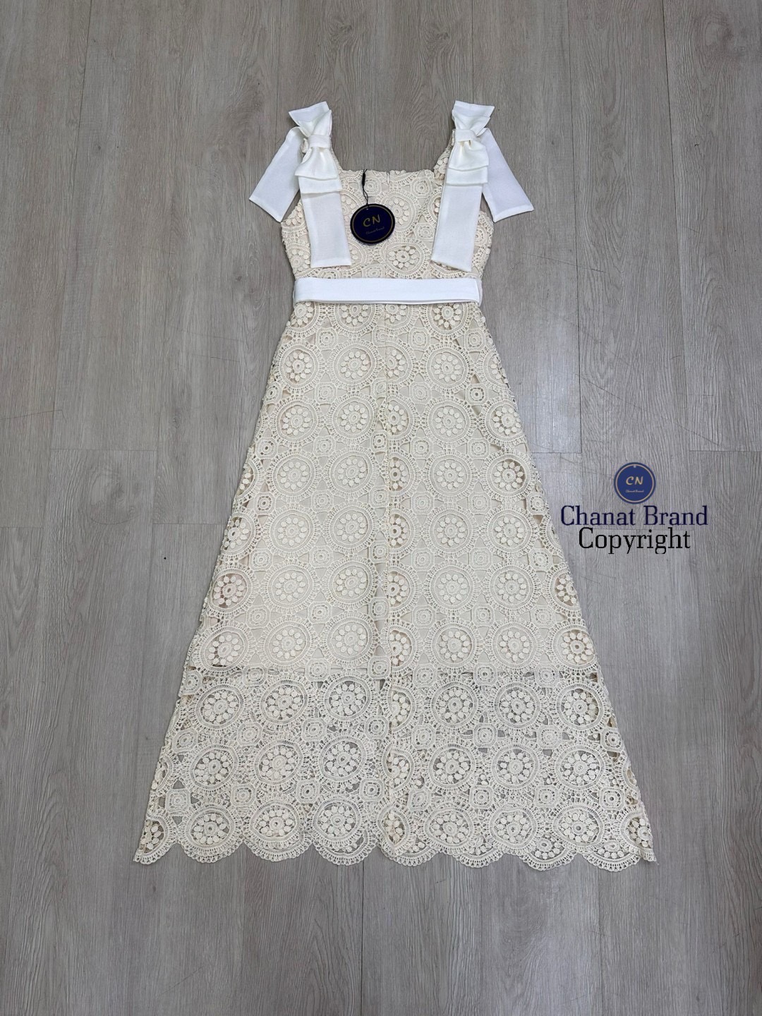 เดรสแฟชั่น เดรสยาวเนื้อผ้าลูกไม้ฉลุวงกลม ดีไซน์แขนกุดตรงบ่าแต่งโบว์ใหญ่สีครีมทั้งสองข้าง