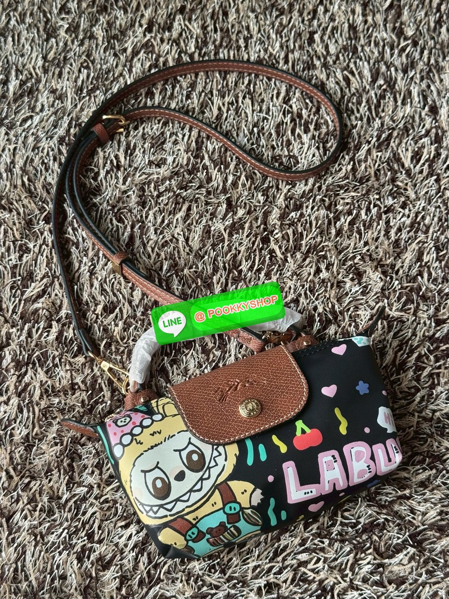 LONGCHAMP LE PLIAGE ORIGINAL X Labubu Pouch with handle เป็นการร่วมงานกัระหว่างแบรนด์ และยังกระเป๋าถือขนาดมินิทรงpouch ที่ด้านหน้ามีลวดลายน้องลาบูบู้ในแบบต่างๆ เปิดปิดระบบสองชั้น ได้ว่าของด้านในมีความปลอดภัย เหมาะอย่างยิ่งสำหรับสาวๆที่ชอบกระเป๋าขนาดมินิไซ