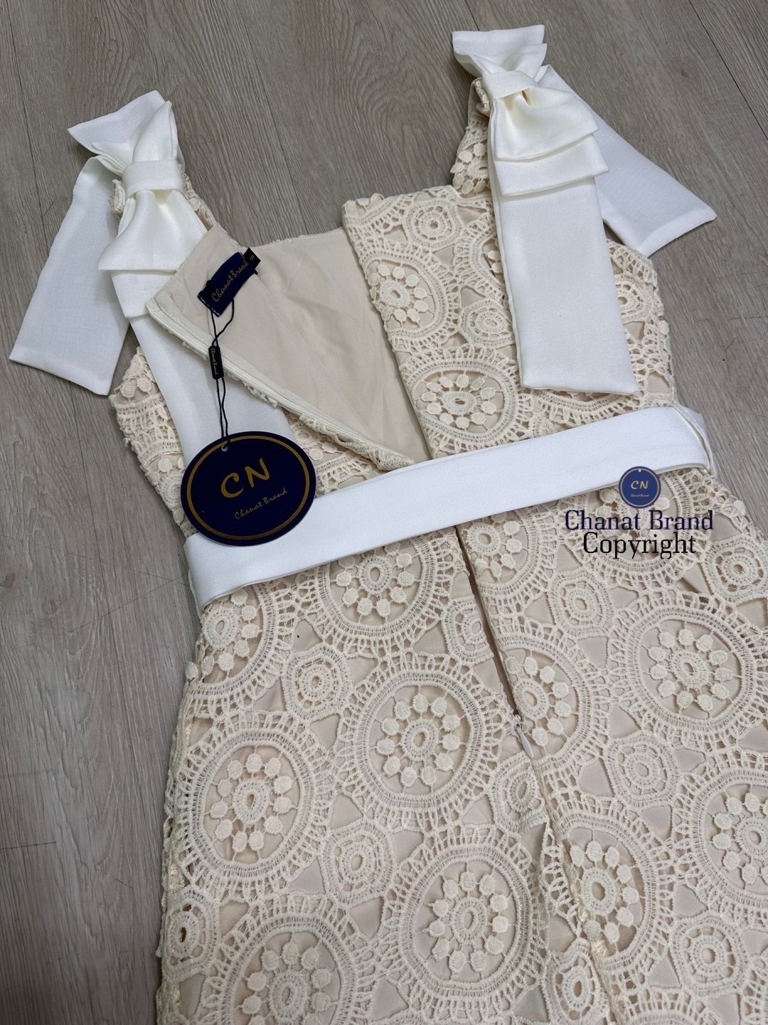 เดรสแฟชั่น เดรสยาวเนื้อผ้าลูกไม้ฉลุวงกลม ดีไซน์แขนกุดตรงบ่าแต่งโบว์ใหญ่สีครีมทั้งสองข้าง