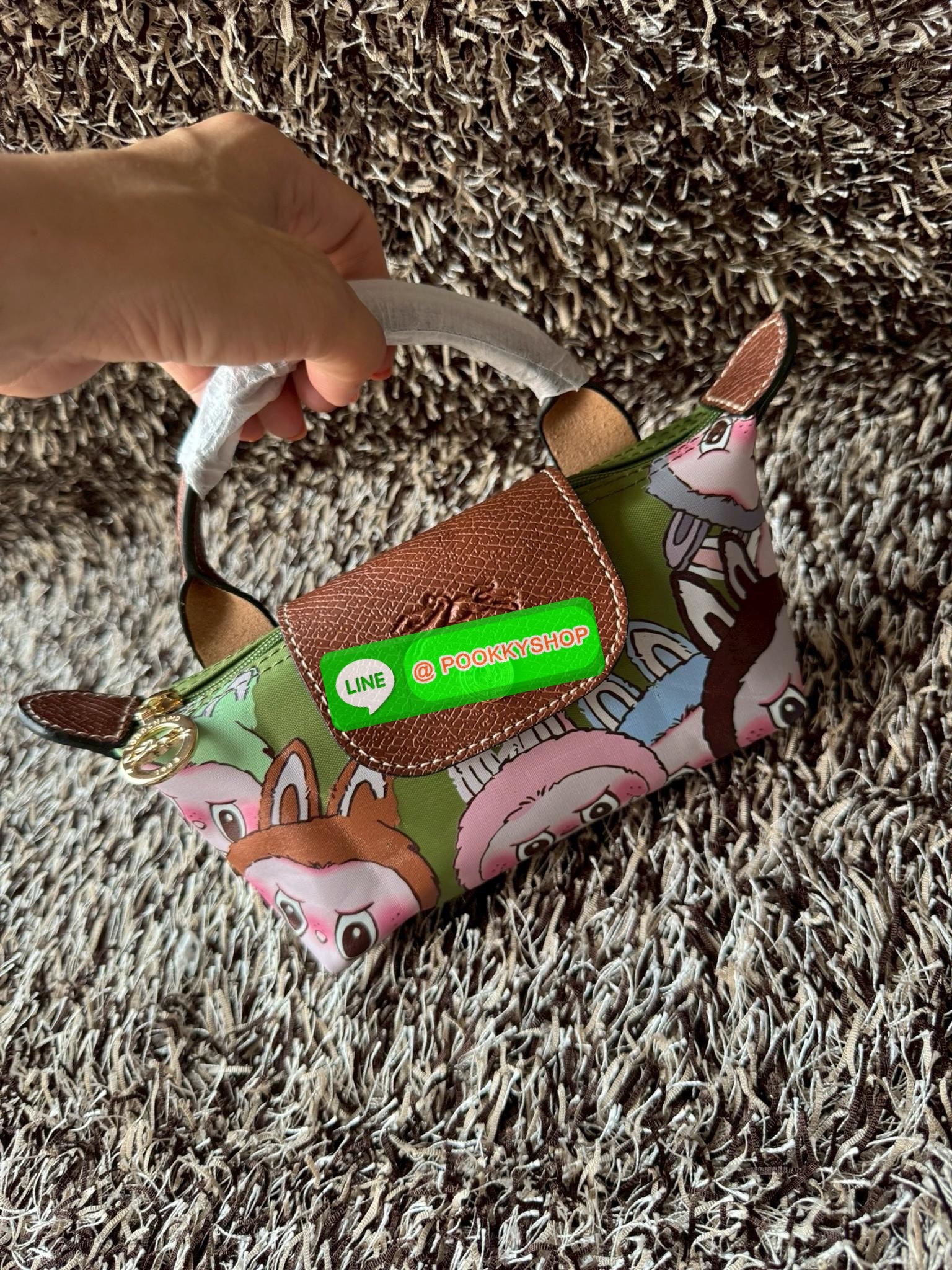 LONGCHAMP LE PLIAGE ORIGINAL X Labubu Pouch with handle เป็นการร่วมงานกัระหว่างแบรนด์ และยังกระเป๋าถือขนาดมินิทรงpouch ที่ด้านหน้ามีลวดลายน้องลาบูบู้ในแบบต่างๆ เปิดปิดระบบสองชั้น ได้ว่าของด้านในมีความปลอดภัย เหมาะอย่างยิ่งสำหรับสาวๆที่ชอบกระเป๋าขนาดมินิไซ